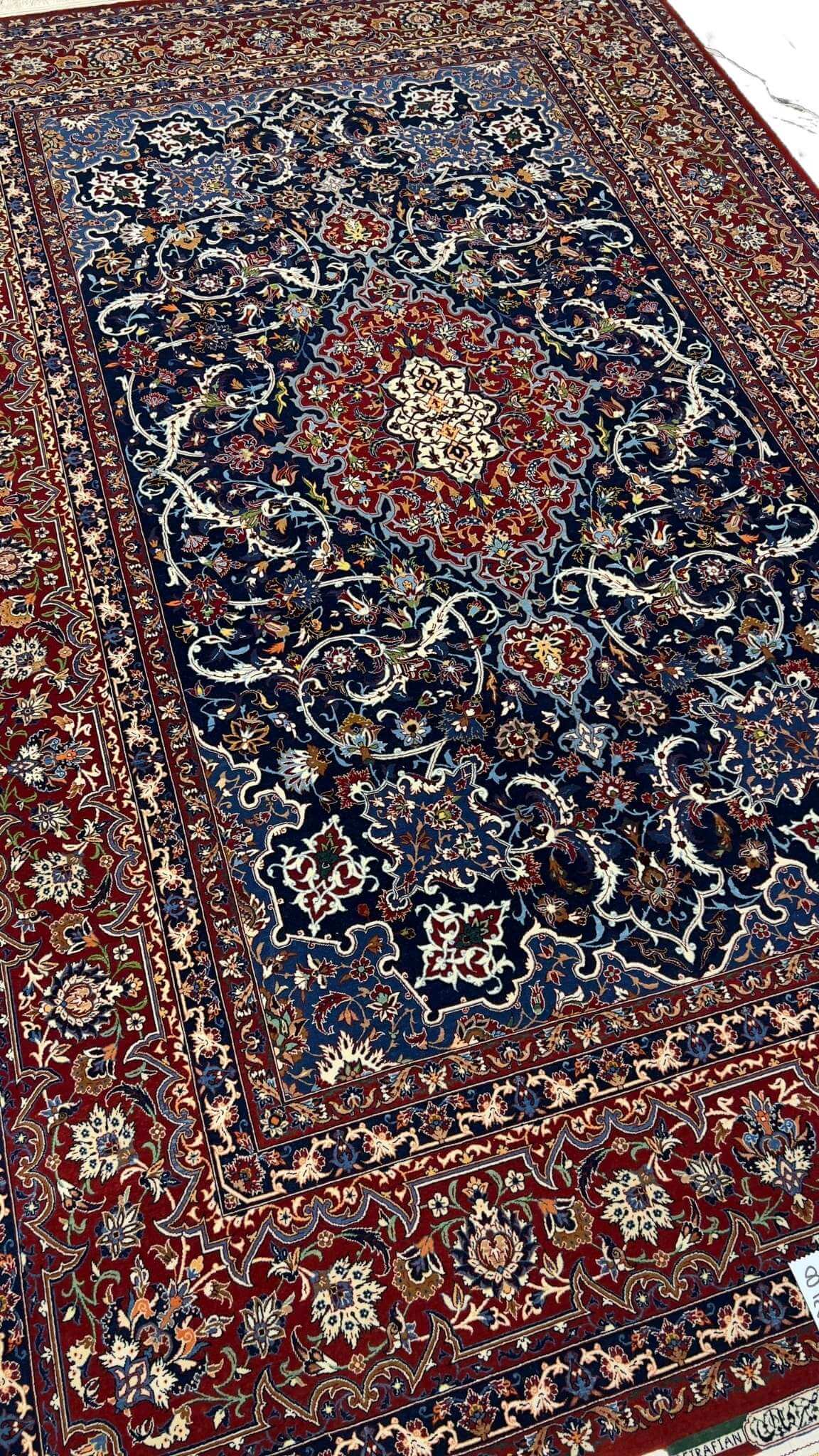 "Luxurious Persian rug featuring navy blue, red, and cream tones, crafted in Isfahan, Iran."